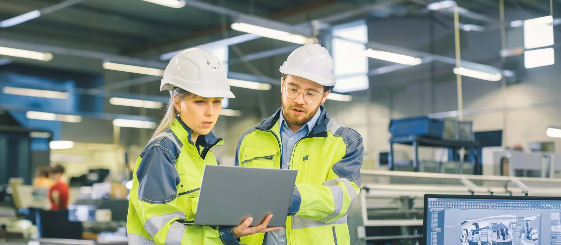 Weiblicher und männlicher Ingenieur in Maschinenraum am Laptop mit Warnweste