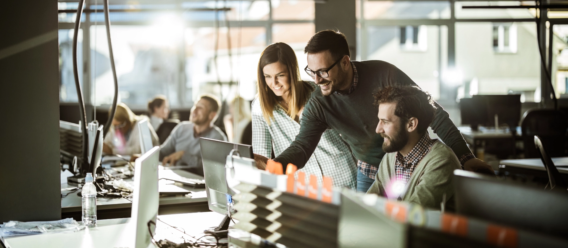 Drei Mitarbeitende der Corporate IT von msg betrachten lachend etwas auf einem Bildschirm