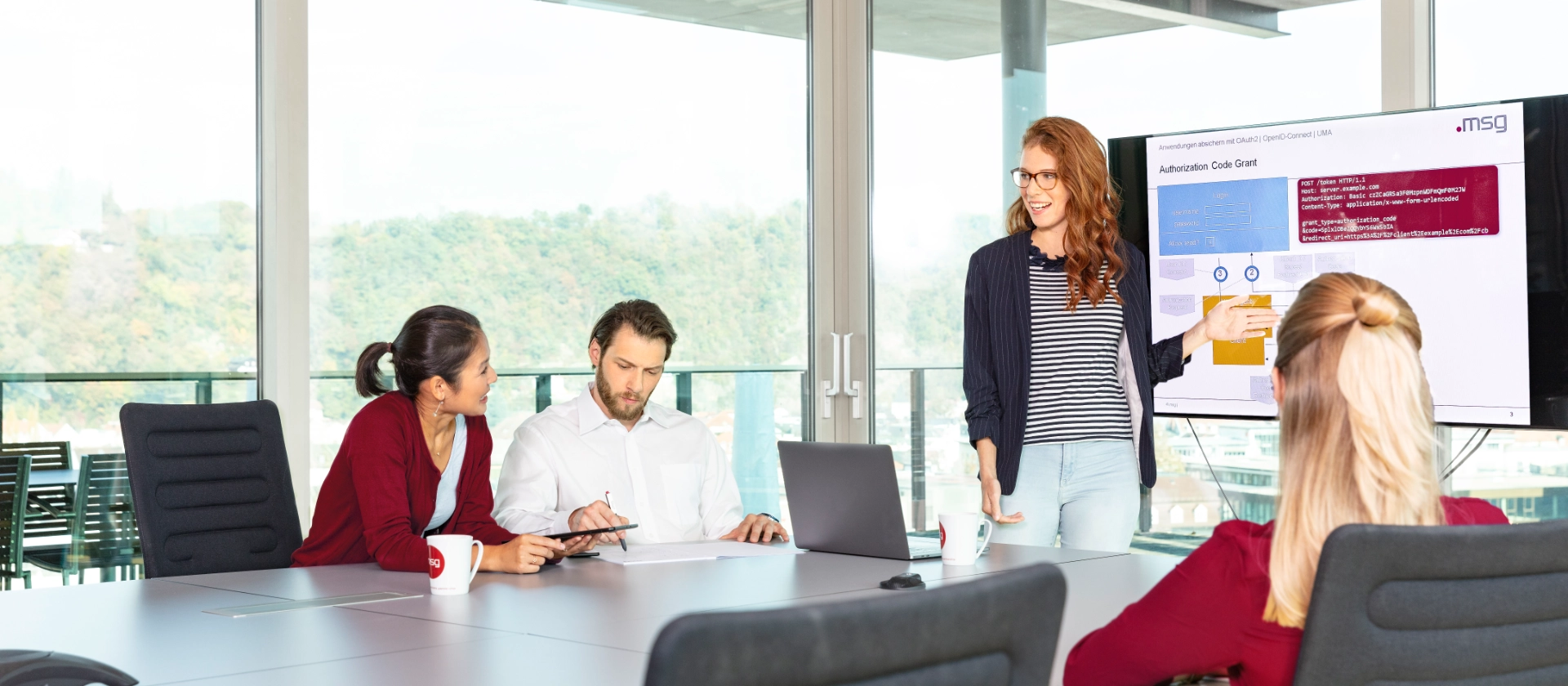 Eine Junior Mitarbeiterin präsentiert in einem Meetingraum etwas ihren Kolleginnen und Kollegen