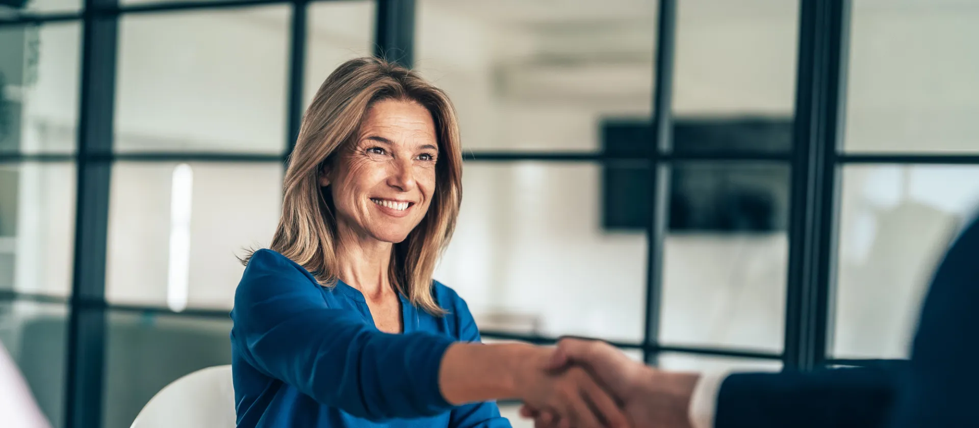 Eine neue Mitarbeiterin schüttelt ihrem Gegenüber die Hände