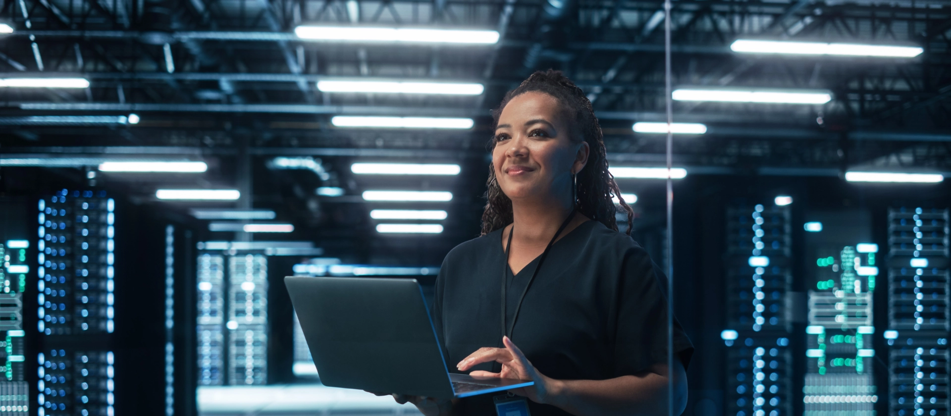 Frau in Serverraum mit Laptop