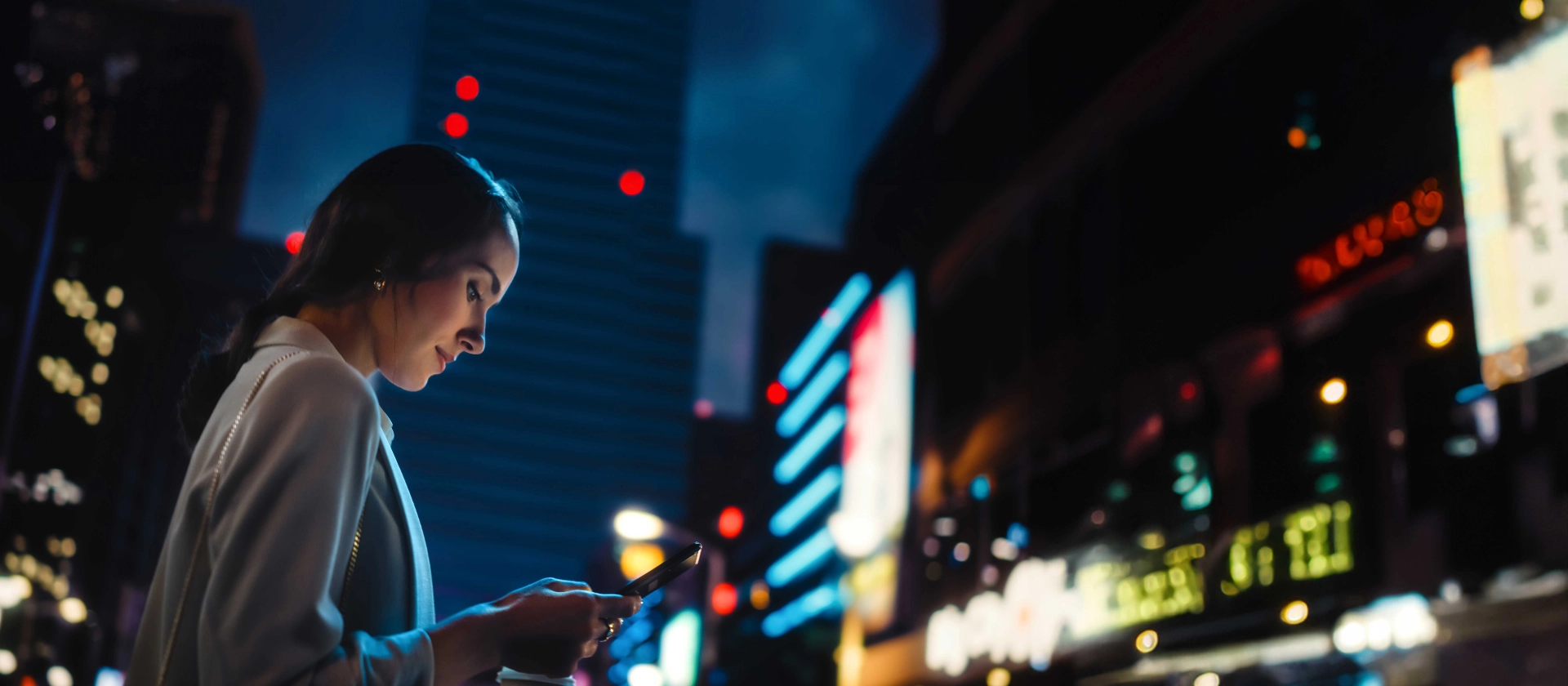 Frau in Stadt vor beleuchteten Hochhäusern