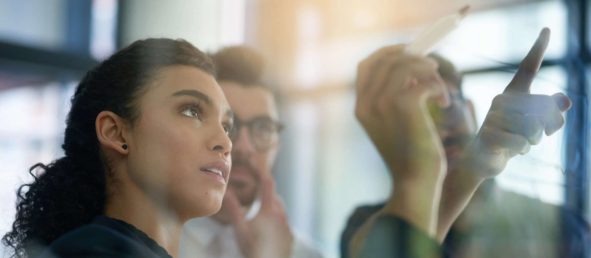 Shot of a group of colleagues brainstorming together on a glass wall in an office.