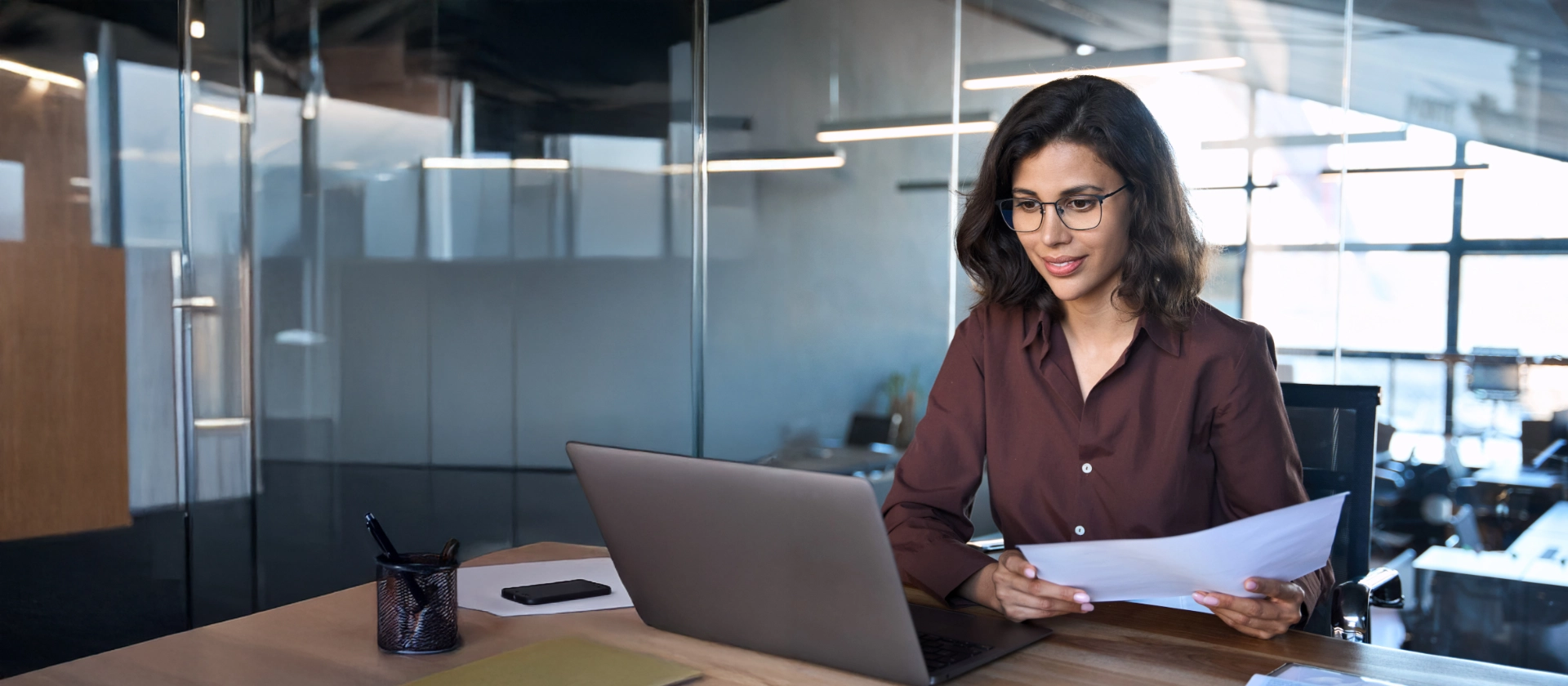 Focused latin hispanic business woman working on laptop computer reading financial document report in office.