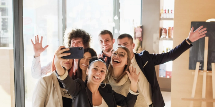 Gemischte Gruppe in Business Casual Outfits machen einen Selfie im Büro und lachen