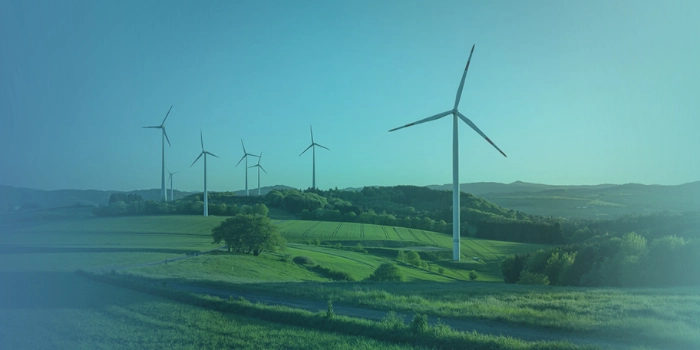 Mehrere Windräder in einer Landschaft, überlagert von blauem Gradient