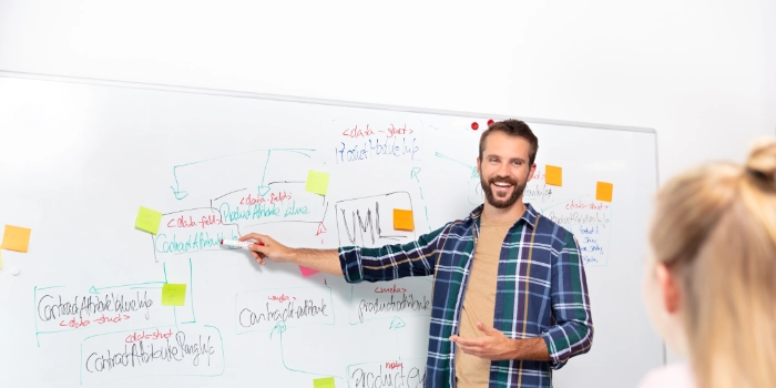 Ein erfahrener msg-Kollege stellt etwas vor einem Whiteboard stehend in einem Schulungsraum vor