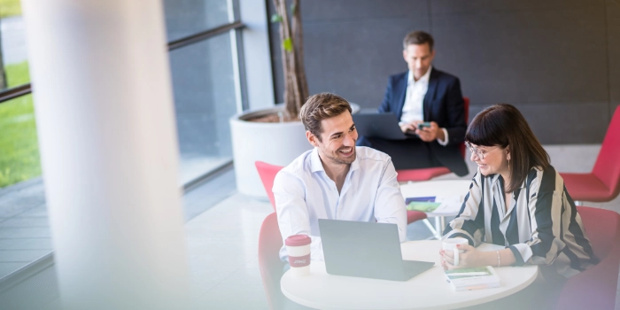 Männlicher und weiblicher Consultant im Foyer von msg in Ismaning bei einem schnellen Meeting an einem Tisch