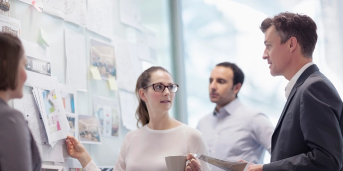 Zwei Frauen und zwei Männer aus der Geschäftseinheit Insurance besprechen sich vor einem Whiteboard mit Notizen