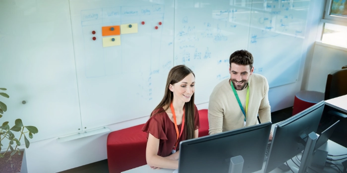 Männlicher und weibliche IT Consultant von oben an ihrem Arbeitsplatz neben einem Whiteboard