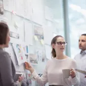 Zwei Frauen und zwei Männer aus der Geschäftseinheit Insurance besprechen sich vor einem Whiteboard mit Notizen