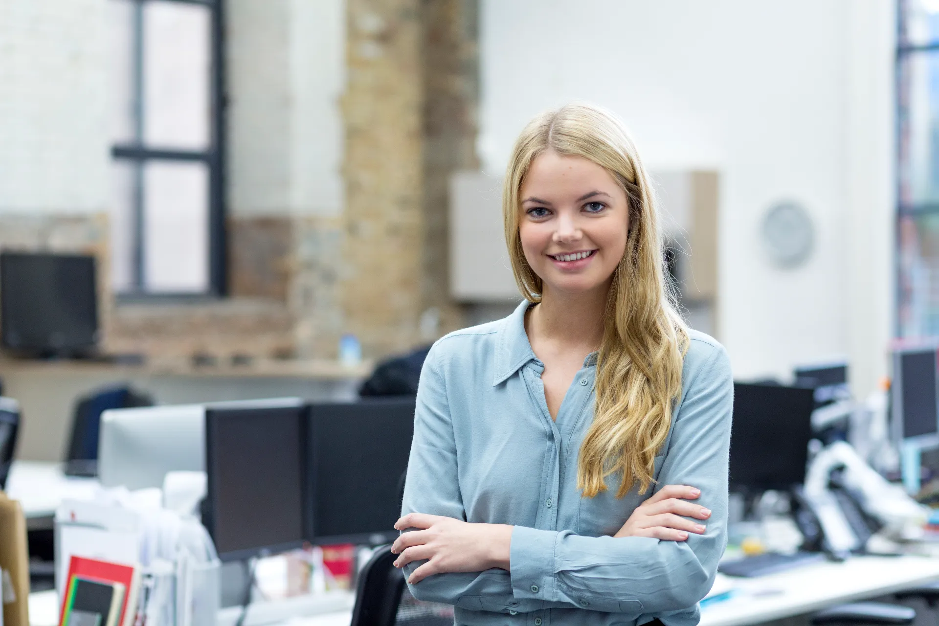 Eine Auszubildende steht in einem Office zwischen Schreibtischen