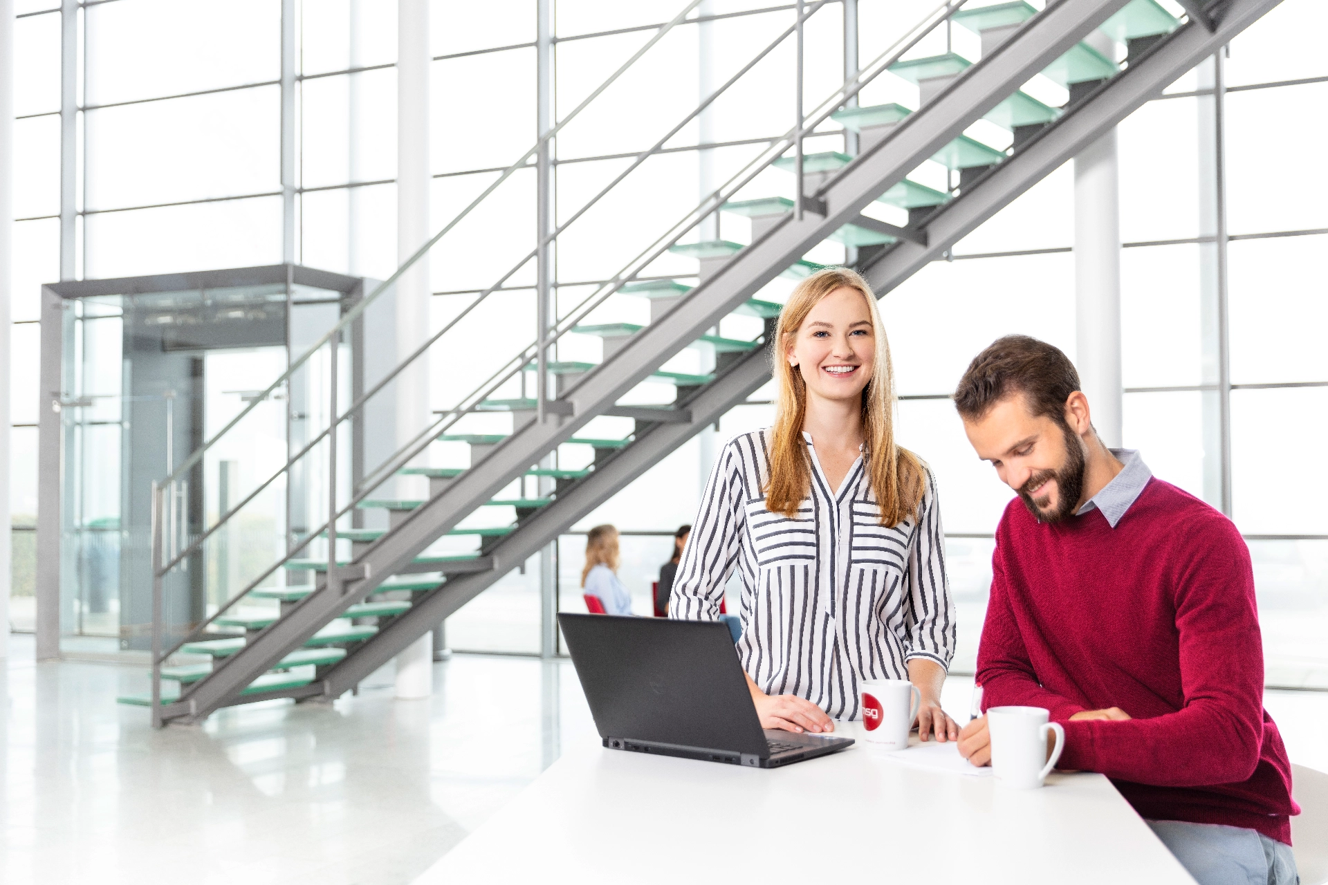 Eine Kollegin und ein Kollege haben ein Meeting im Foyer der msg-Firmenzentrale Ismaning
