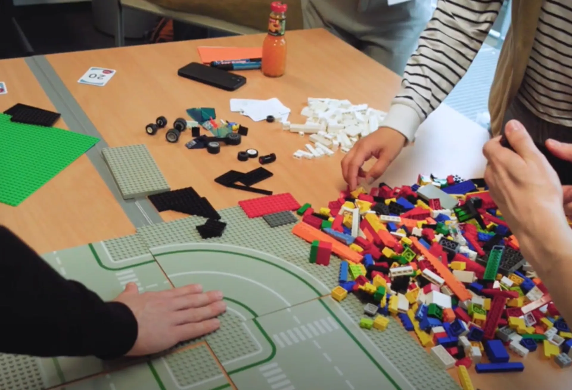 Hände von Studierenden, die LEGO-Steine zusammensetzen