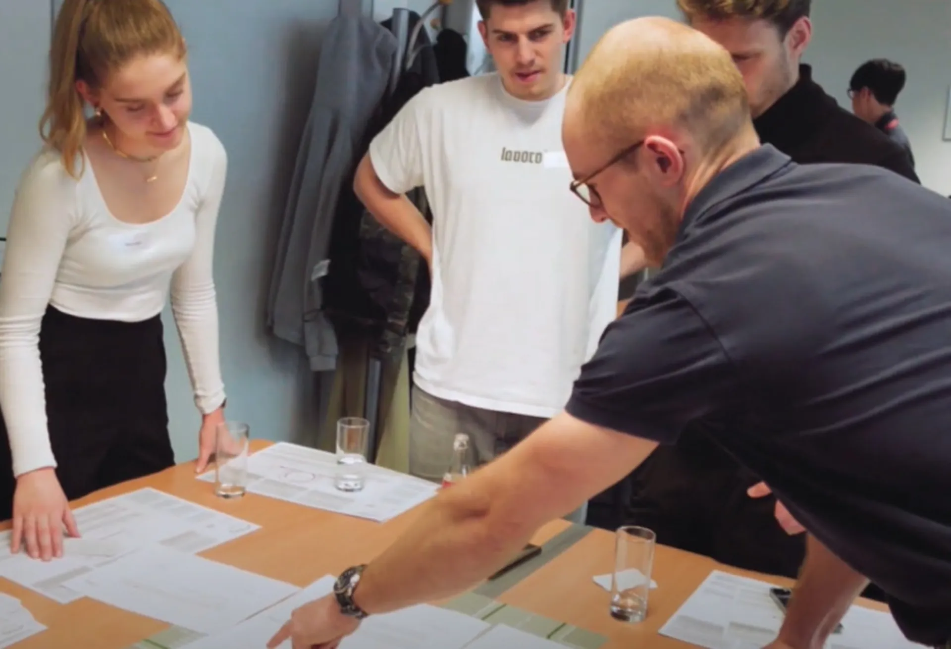 Ein msg-Kollege erklärt Studierenden anhand von Skizzen auf dem Tisch das Scrum-Prinzip